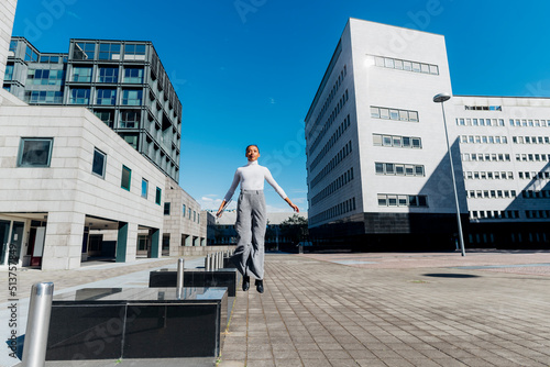 Businesswoman jumping at financial district on sunny day