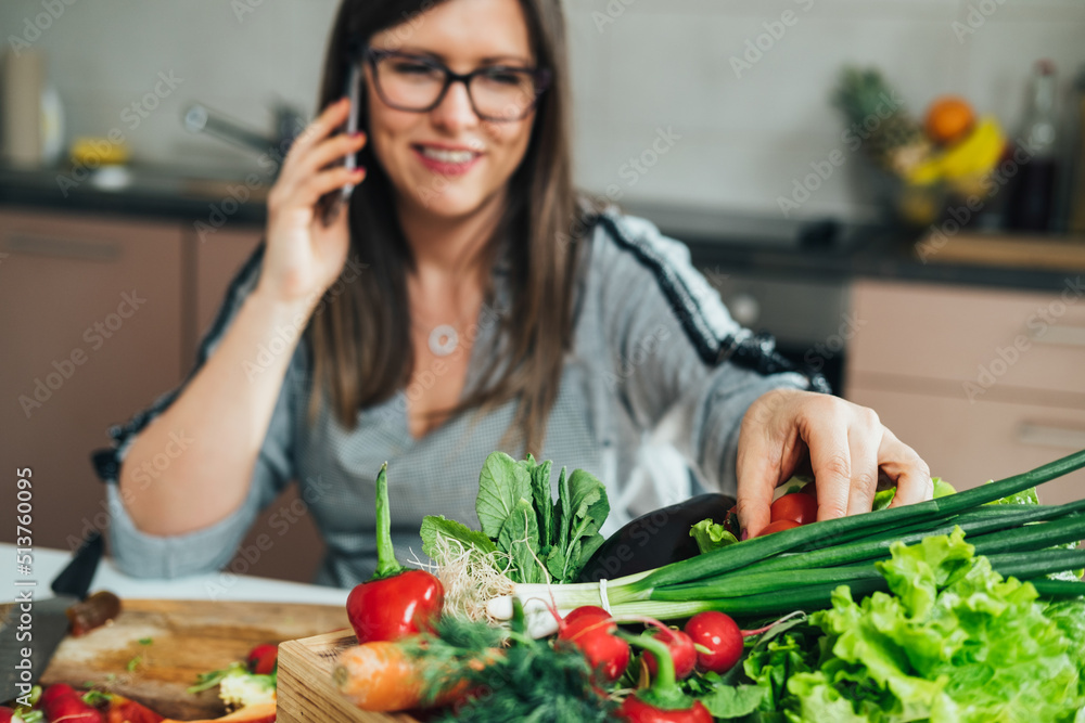 An Anonymous Woman Talking on a Mobile Phone while Making Healthy Lunch with Colorful Vegetables in the Kitchen An Anonymous Woman Talking on a Mobile Phone while Making Healthy Lunch with Colorful Vegetables in the Kitchen