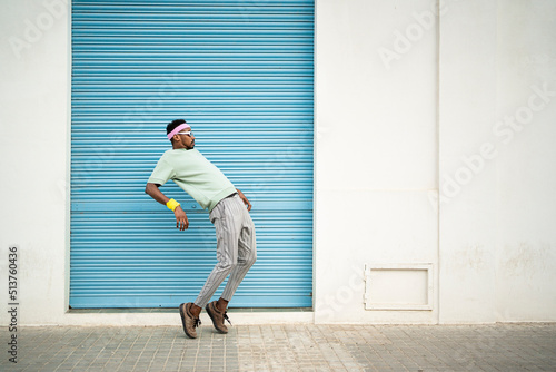 Flexible young man dancing on footpath in front of blue shutter photo