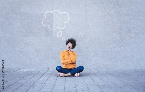 Woman sitting cross-legged on ground with empty thought bubble photo