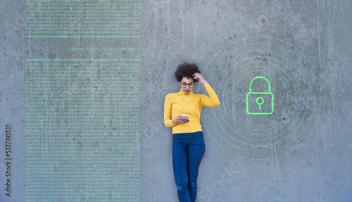 Confused woman looking at smartphone with data lock painted on wall photo