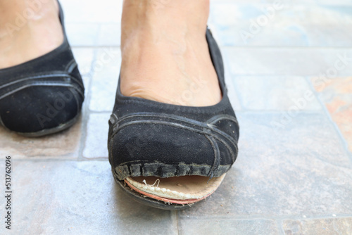 Torn women's shoes in the street, Torn shoe on foot, Footwear requiring repair