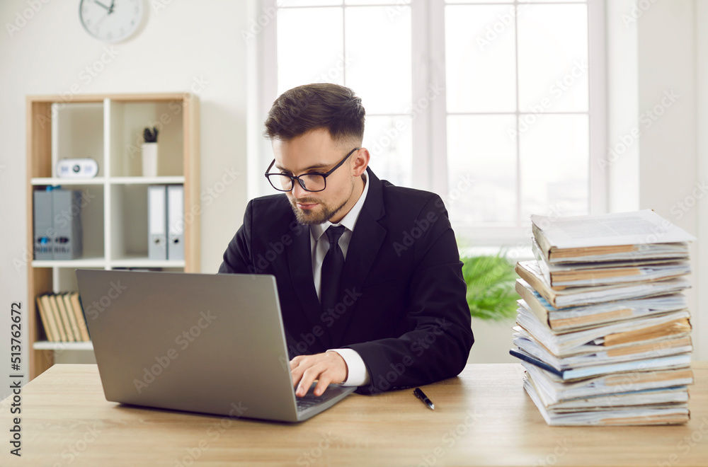 Busy bookkeeper does not like dealing with piles of paper documents and works on modern laptop instead. Company accountant uses computer having easy access to all files in enterprise digital database Busy bookkeeper does not like dealing with piles of paper documents and works on modern laptop instead. Company accountant uses computer having easy access to all files in enterprise digital database