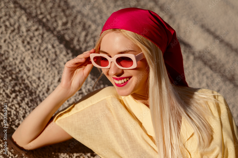 Happy smiling fashionable woman wearing pink sunglasses, satin bandana. Copy, empty space for text Happy smiling fashionable woman wearing pink sunglasses, satin bandana. Copy, empty space for text
