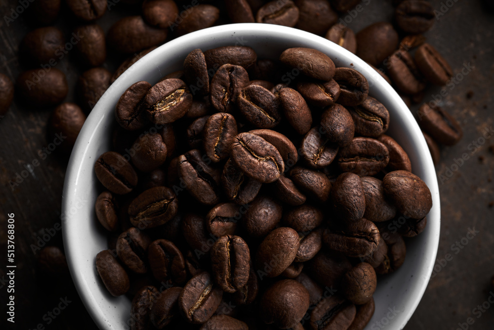 Naklejka premium Roasted coffee beans in bowl isolated close up on brown grunge background