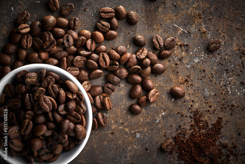 Roasted coffee beans in bowl isolated close up on brown grunge background