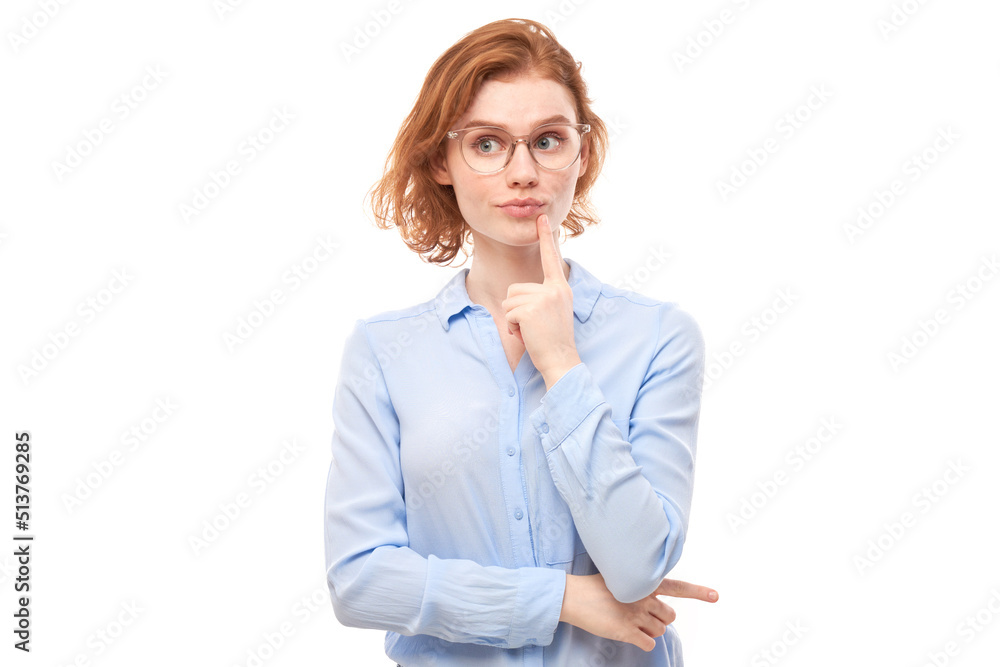 Smart redhead girl in glasses and business shirt holding chin thinks doubts, makes decision isolated on white studio background Smart redhead girl in glasses and business shirt holding chin thinks doubts, makes decision isolated on white studio background