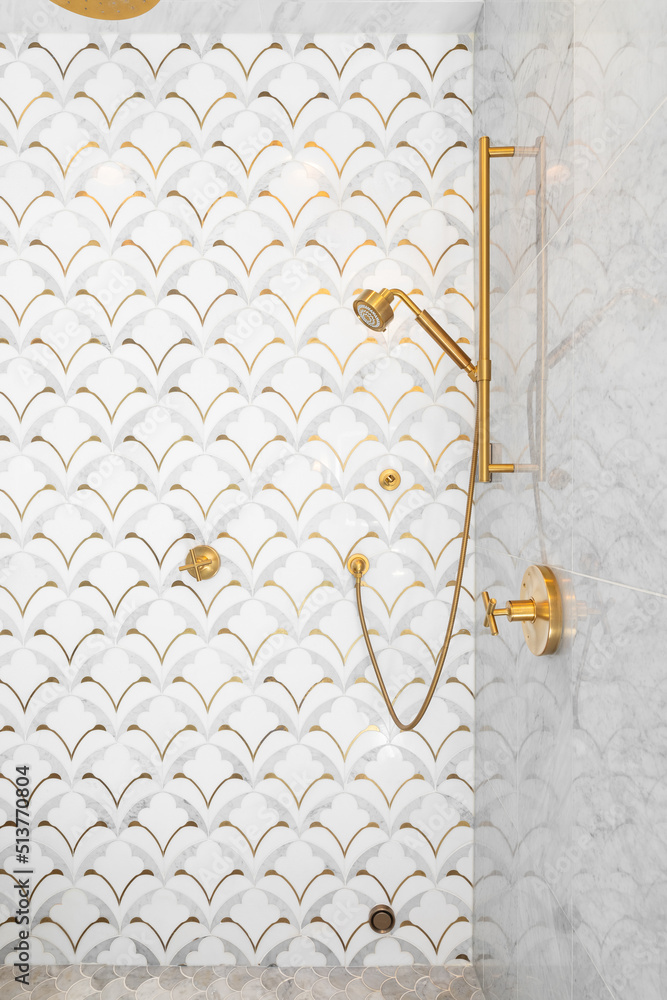 A beautiful tiled shower with gold and white tiles on the walls, mosaic