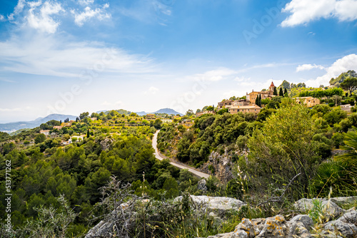 Panoramic view towards the Mallorca west coast over the mountain village Galilea in summer with a small church called Parroquia de Galilea located at a hilltop above road MA1032 and a pine tree forest photo