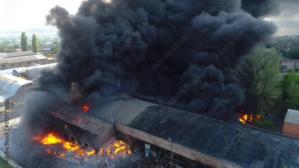 Rocket attack on the plant. Warehouse building strong fire in warehouses black smoke and fire. Shooting from a drone over a large-scale fire. Grain video. Rescuers put out a huge fire Rocket attack on the plant. Warehouse building strong fire in warehouses black smoke and fire. Shooting from a drone over a large-scale fire. Grain video. Rescuers put out a huge fire