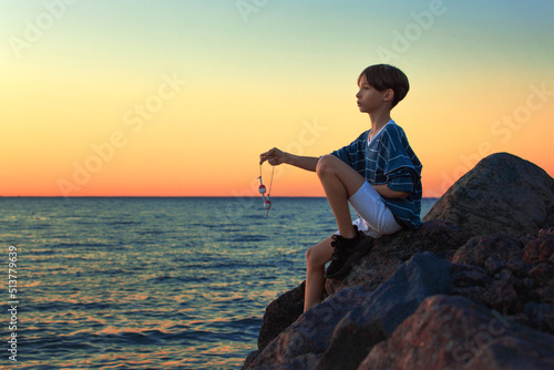 child sits on the seashore at sunset  summer vacation
