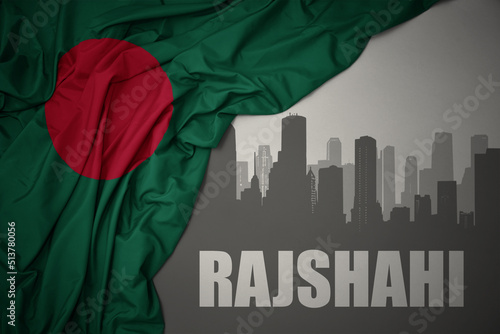abstract silhouette of the city with text Rajshahi near waving national flag of bangladesh on a gray background. photo