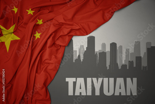 abstract silhouette of the city with text Taiyuan near waving national flag of china on a gray background. photo