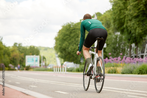 The young man rides a bicycle along the river embankment. A cyclist riding a bike around the city. Photo from the back. Outdoor vacation concept.