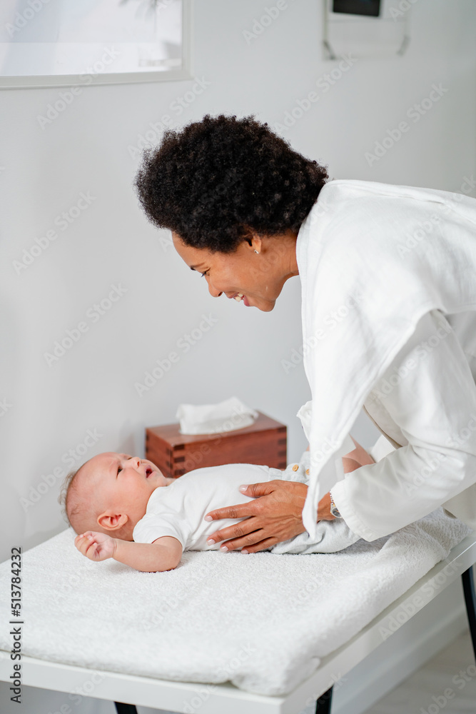 Fototapeta premium Female doctor pediatrician examining an infant child at her office