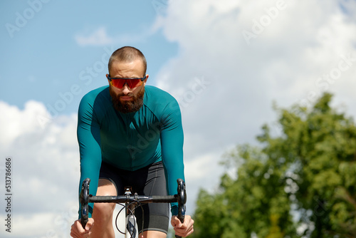 Portrait of a sporty man in a cycling outfit standing with a bicycle on the Bike Lane, posing for the camera