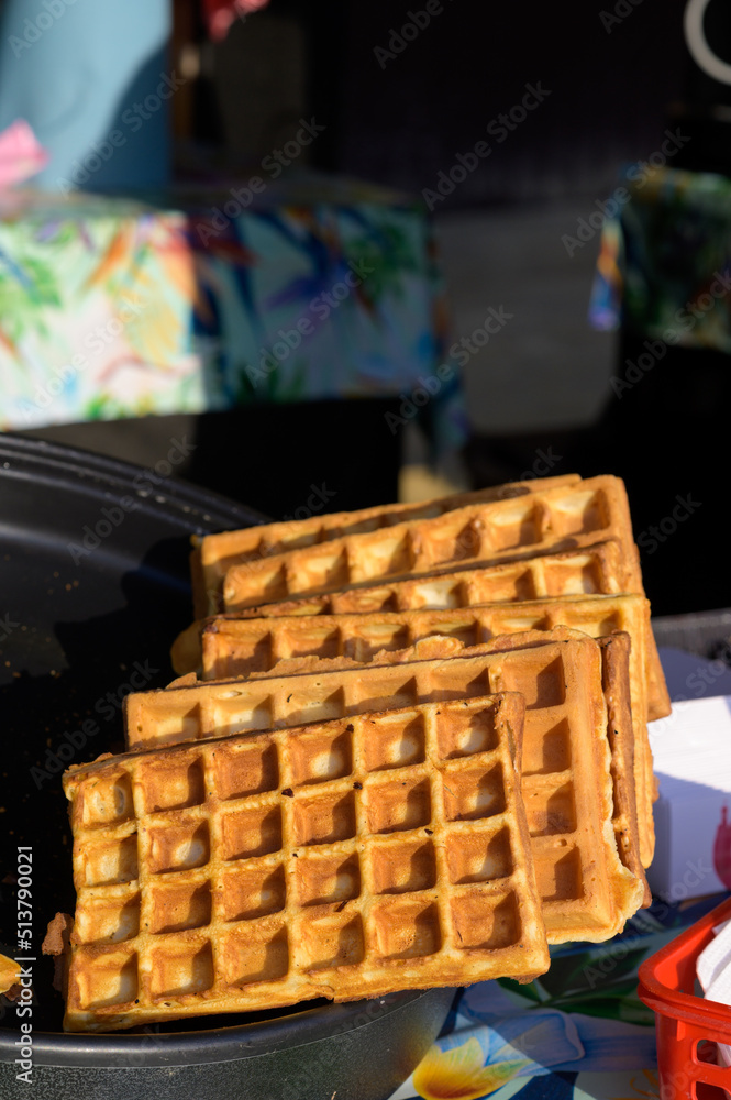 Close up of rustic traditional waffle at street food festival. Outdoor cooking service gastronomy and takeaway food concept Close up of rustic traditional waffle at street food festival. Outdoor cooking service gastronomy and takeaway food concept