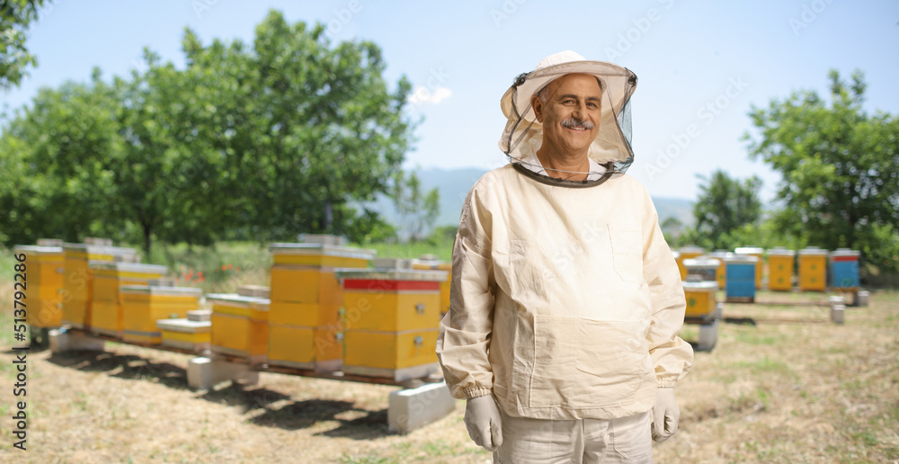 Smiling male bee keeper in a uniform posing on a bee farm Smiling male bee keeper in a uniform posing on a bee farm