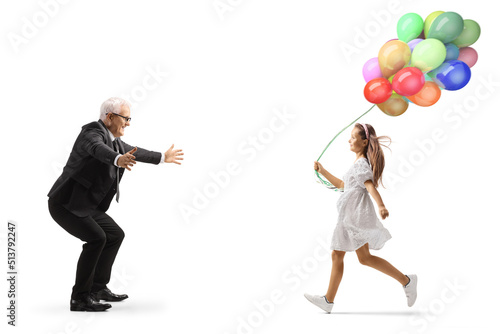 Full length profile shot of a girl with balloons running towards a businessman