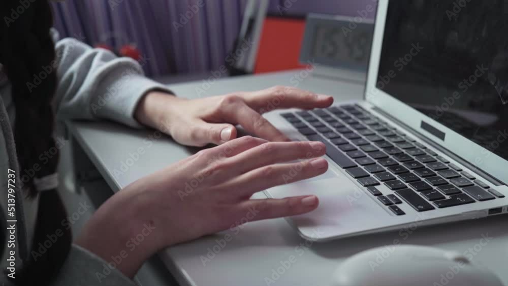A woman's hand operates the tutchpad on a laptop while working on a computer. A woman's hand operates the tutchpad on a laptop while working on a computer.