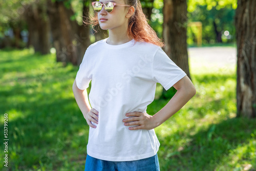 Teenage girl in white tee basic youth apparel shoot. Sportswoman in sunglasses in full face on a walk in the city park. Solid color clothing with space for text or pattern. 