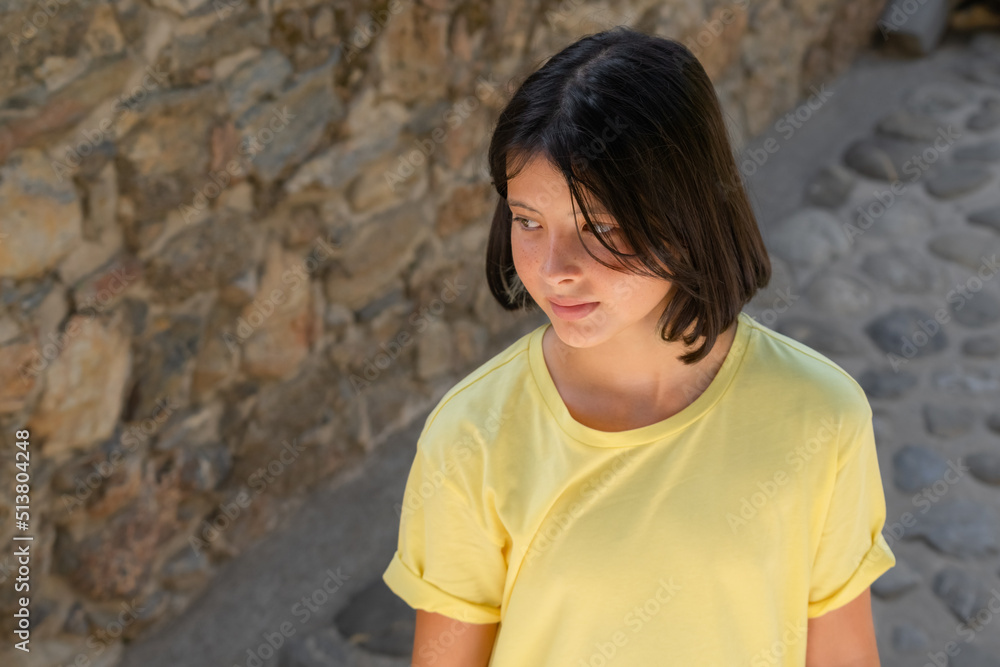 Portrait of a teenage girl against the background of a wall and a stone road. Portrait of a teenage girl against the background of a wall and a stone road.