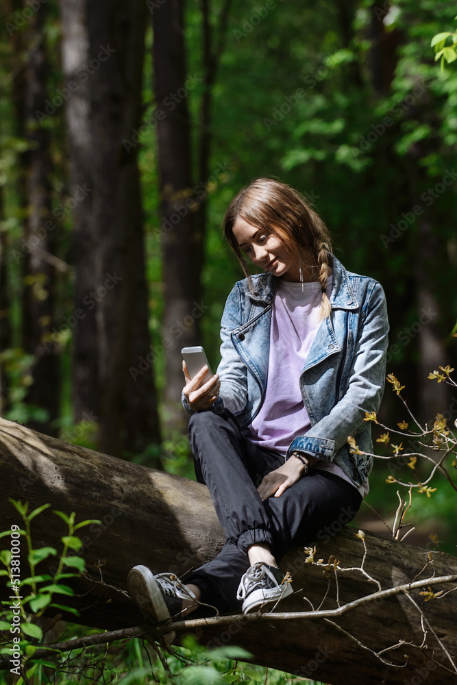 a beautiful girl in a green forest on a walk talking on the phone in the warm season a beautiful girl in a green forest on a walk talking on the phone in the warm season