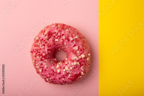 Donut on a pink background.Strawberry donut with pink icing and sprinkles on a paper background.Colorful minimalism concept.Junk food.Sweets.Copy space.Flat lay.Place for text.