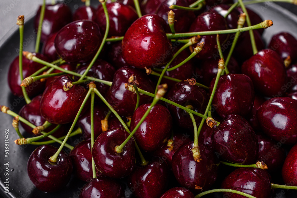 Fresh sweet cherries plate with leaves in water drops on stone background, top view Fresh sweet cherries plate with leaves in water drops on stone background, top view