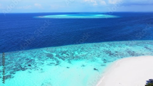 Tropical atoll island in Maldives with coral reef and turquoise sea water. Touristic vacation holidays travel destination. Scenic seascape. Drone aerial video footage. photo