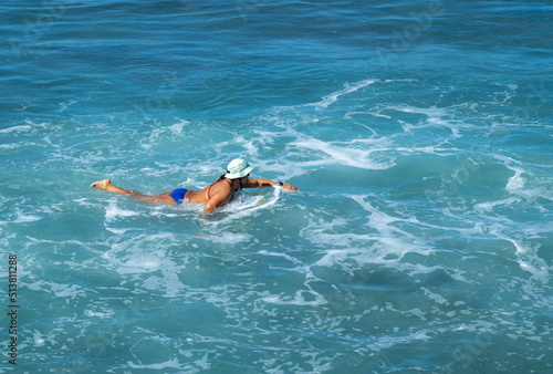 Woman Swimming in Turquoise Blue Ocean Water While Wearing a Sun Hat.