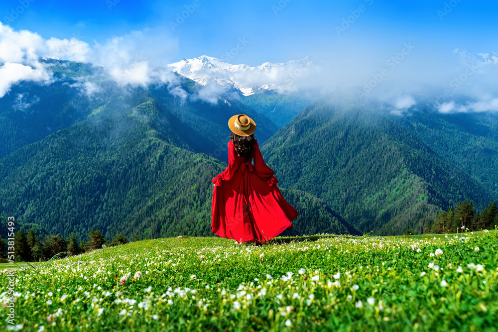 Tourist enjoy view of green pasture and flowers near snow mountain in Georgia.