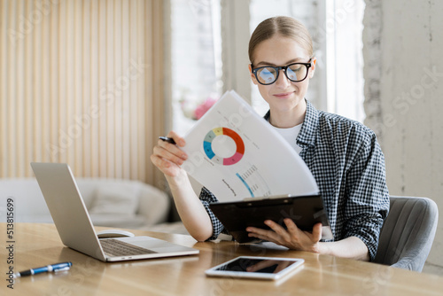 Foto Financier a woman with glasses works, uses a laptop, makes a report to a finance