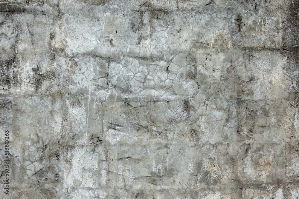 Fragment of an old gray plastered wall. Through the surface, covered with irregularities and cracks, stone blocks appear. Grunge. Background. Texture.