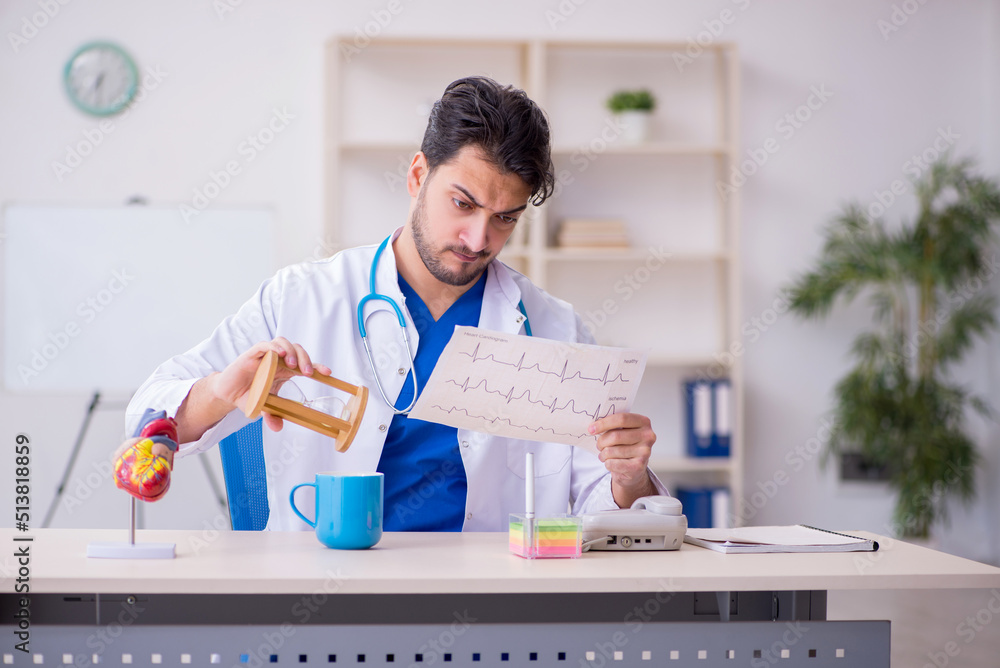 Young male doctor cardiologist in time management concept Young male doctor cardiologist in time management concept