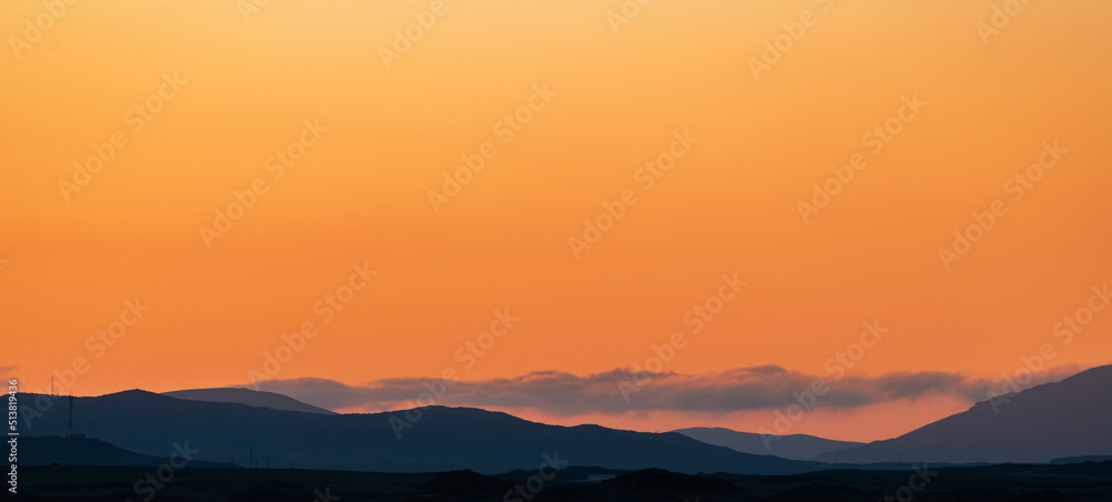 Bright orange sunset in the silhouette mountains.  