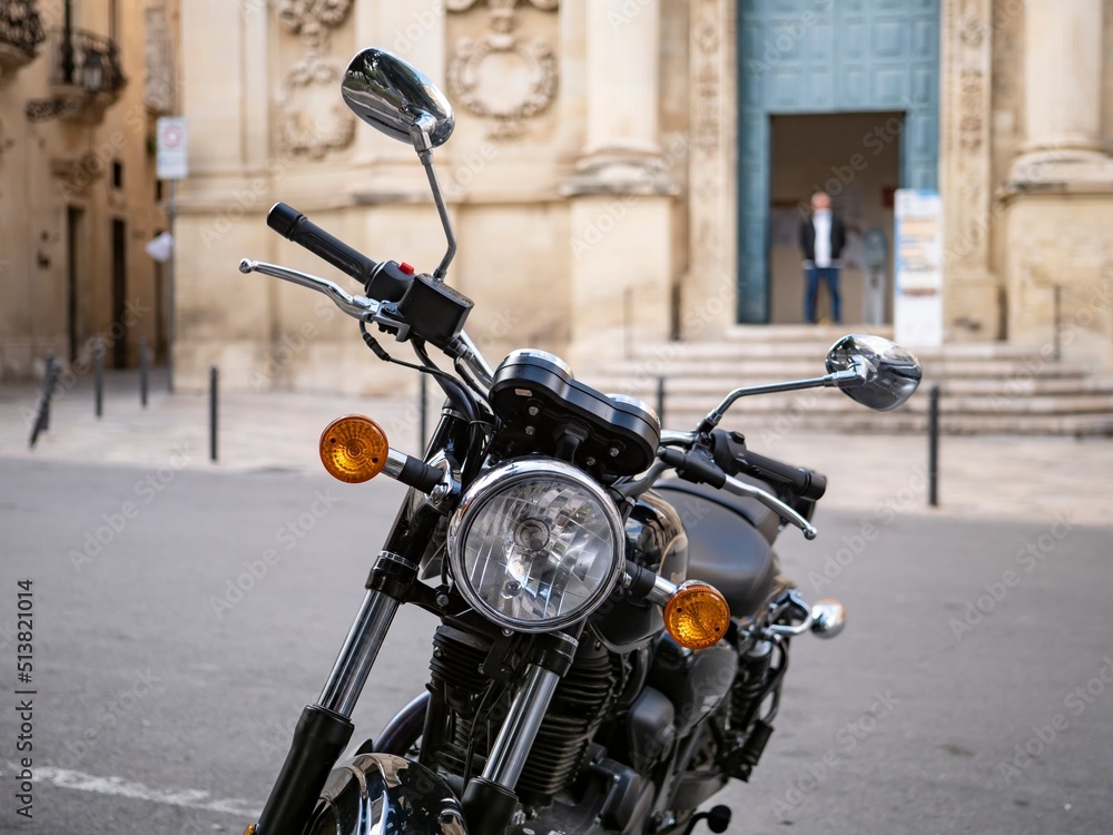 Headlamp of historical motorcycle in front of a church in Lecce, Italy