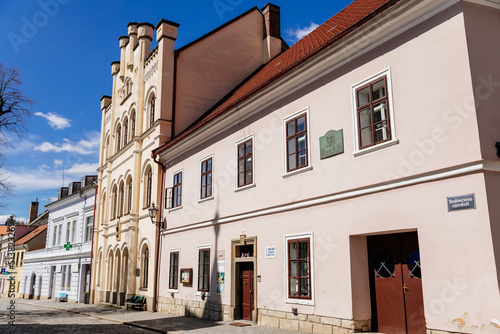 Litomysl, Czech Republic, 17 April 2022: narrow picturesque street with medieval colorful gothic merchant houses at sunny summer day, historic renaissance and baroque buildings, medieval church