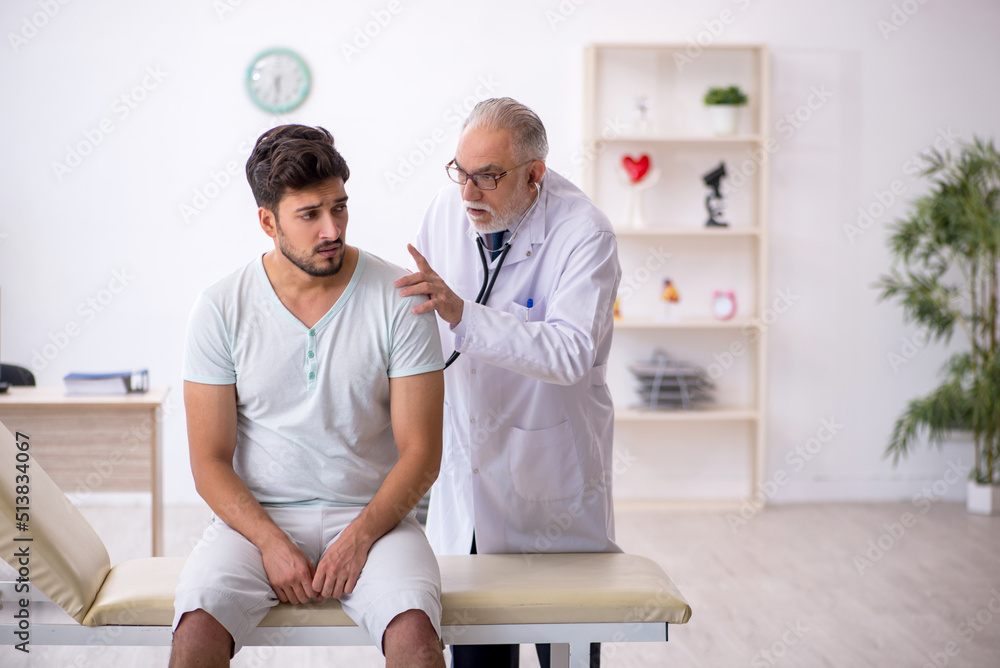 Fototapeta premium Young male patient visiting old male doctor