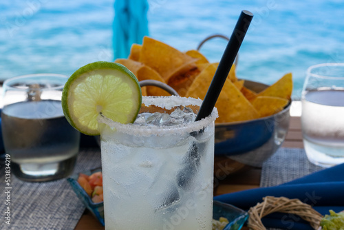Agave margarita cocktail with chips and salsa in a dinner sitting on a tropical island. 