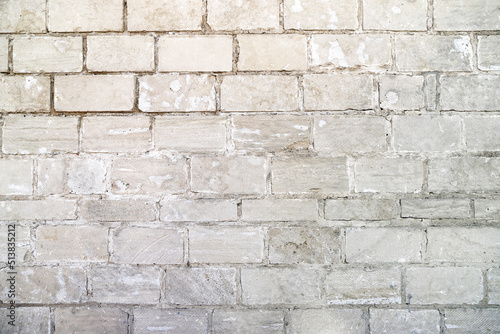 An old damaged wall made of white bricks as a background