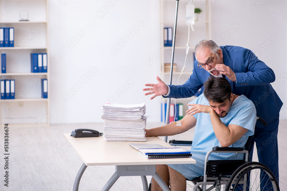 Young male employee in wheel-chair feeling bad at workplace Young male employee in wheel-chair feeling bad at workplace