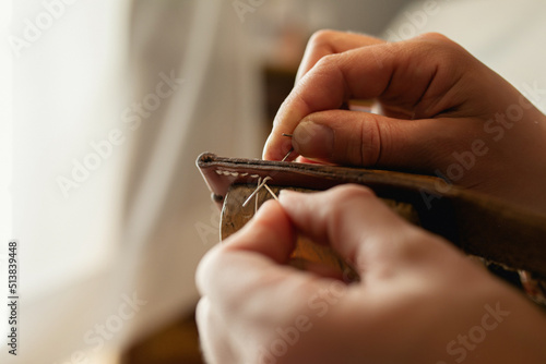 Handmade. Making elements for a leather belt with your own hands. Machining a metal buckle with a file and a hammer in a workshop. atmospheric photo