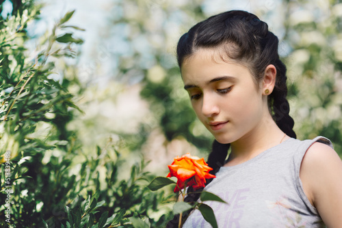 Obraz na płótnie Nice emotion of cute little girl holding and looking down at rose in garden w salonie