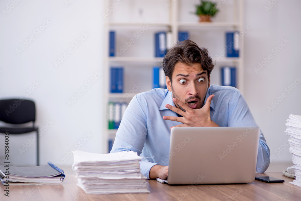 Young male employee and too much work in the office Young male employee and too much work in the office