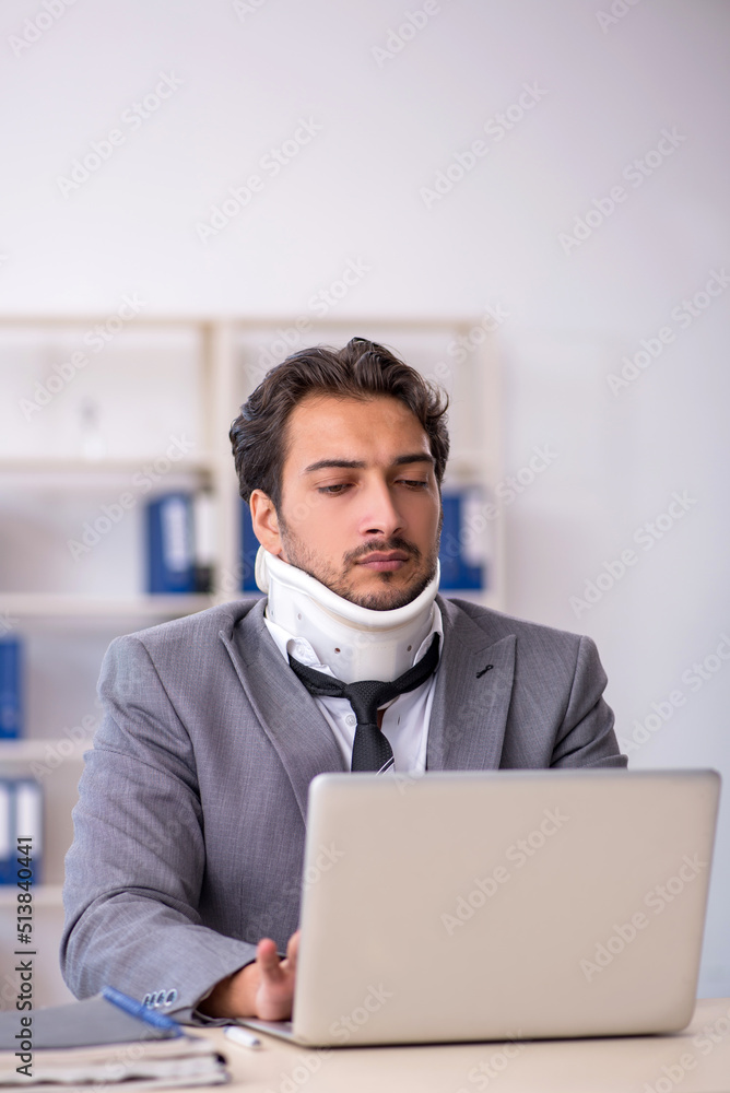 Young male employee after car accident working in the office Young male employee after car accident working in the office