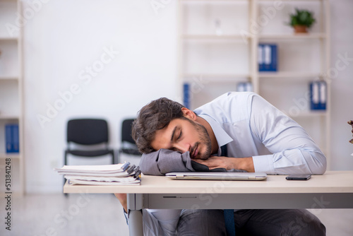 Foto Young male employee in oversleeping concept