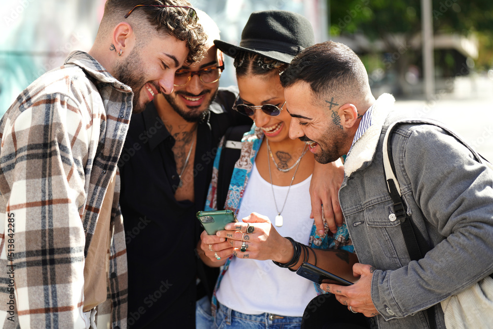 Happy group of friends watching social media on screen mobile phone, laughing. Young people using smartphone, having fun together in the city. Happy group of friends watching social media on screen mobile phone, laughing. Young people using smartphone, having fun together in the city.