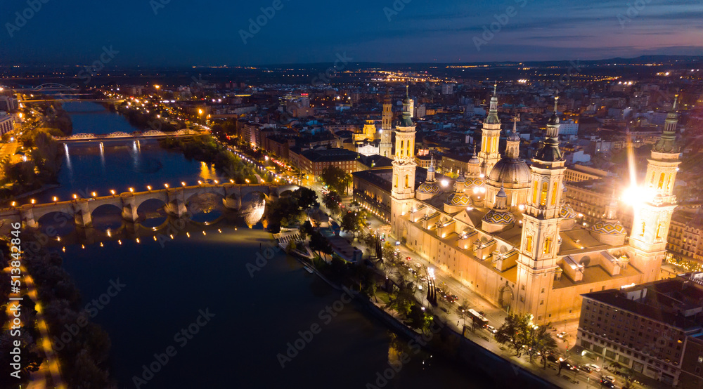 Scenic twilight view from drone of illuminated Basilica of Our Lady of Pillar on bank of Ebro river in Spanish city of Zaragoza ..