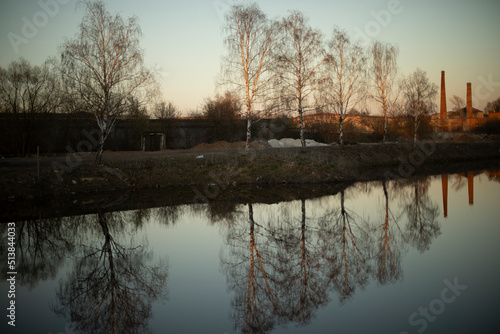 View of lake. Reflection in water. Details of outskirts of city.